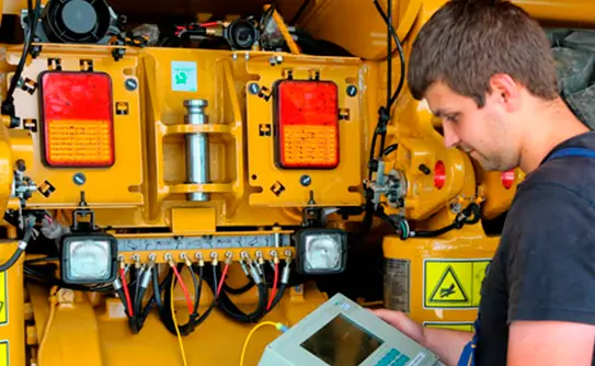 Técnico instalando sistema eléctrico en maquinaria pesada